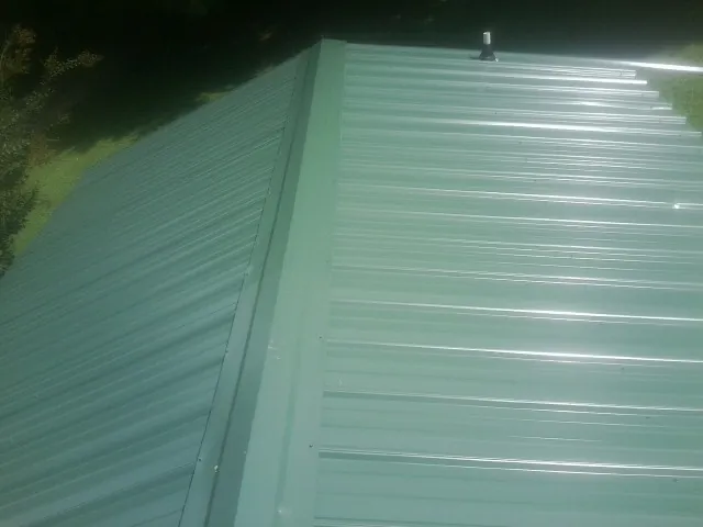 New green metal panels meeting at the ridge of a roof — Flat Roof Repair work by our crew in Edwards