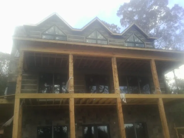 Dormers and porch framing on a large log home under construction — Roof Coating work by our crew in Edwards